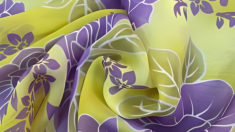 a luxurious silk fabric featuring a vibrant yellow and purple floral print, showcasing intricate floral designs.