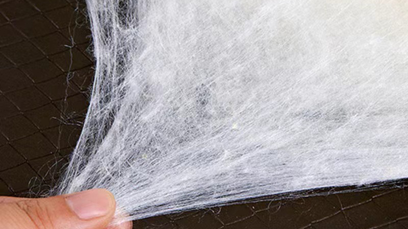 a person holds a delicate piece of white silk fabric, showcasing its smooth texture and elegant appearance.