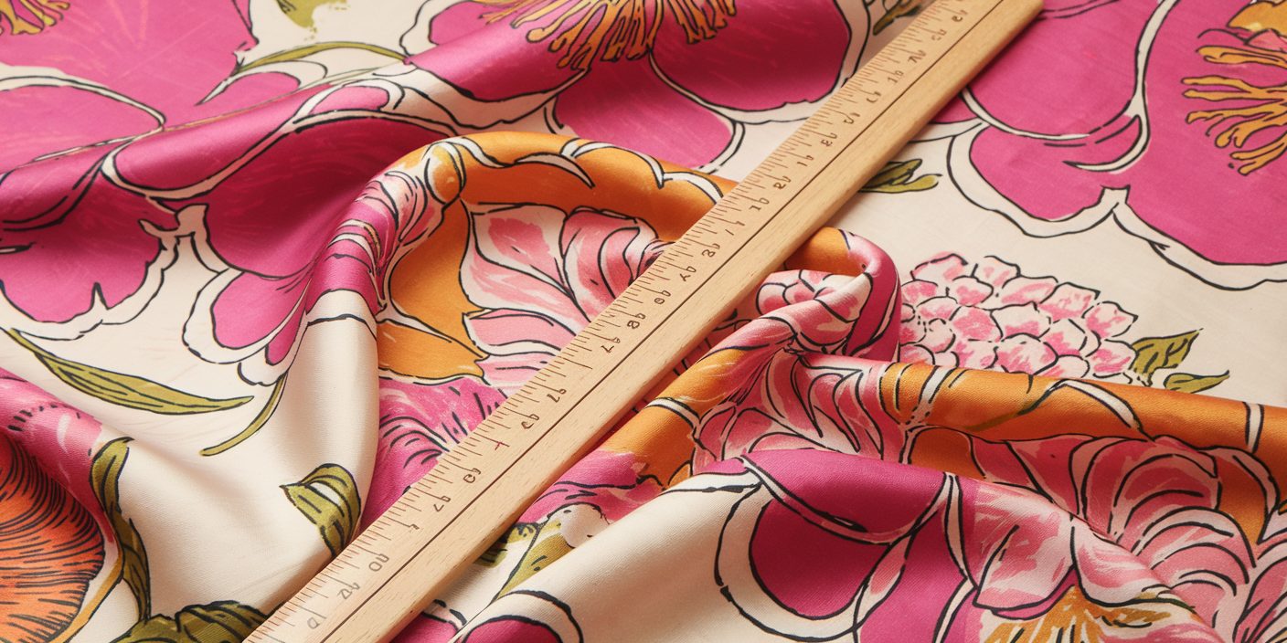 a ruler placed beside a vibrant pink and orange floral print fabric, showcasing a blend of colors and patterns